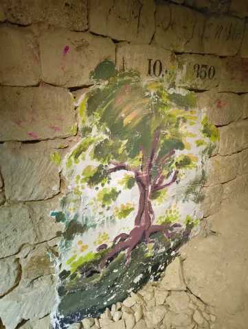 Arbre peint à la gouache sur un mur de pierre, sous une date gravée du XIXe siècle