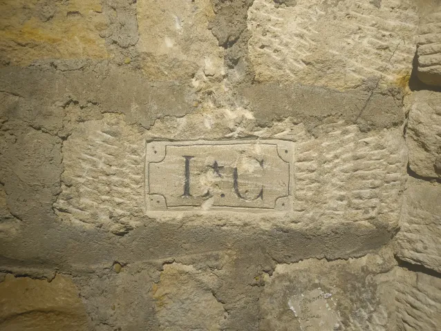 Cartouche gravé aux initiales « I.G » dans un mur de pierre de taille