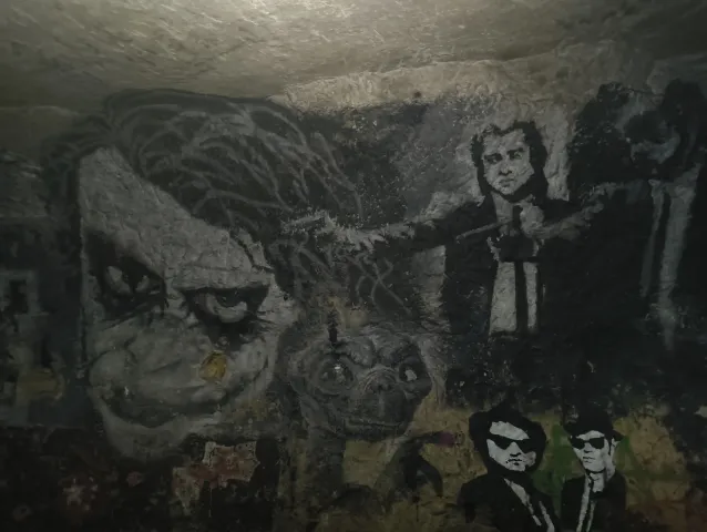 Fresque sombre réunissant plusieurs personnages de cinéma peints sur la paroi