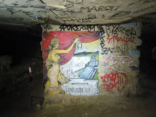 Fresque d'une femme drapée de rouge dévoilant une scène souterraine, intitulée « Inauguration »