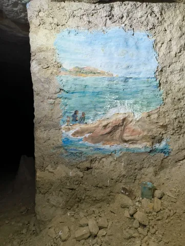 Fresque d'une vague et d'un bord de mer peinte sur un pilier de calcaire brut