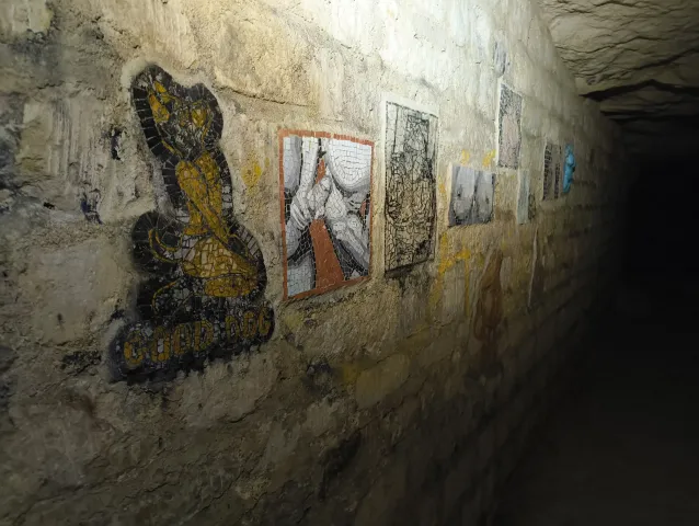 Suite de l'exposition souterraine : peintures et estampes alignées sur la paroi éclairée