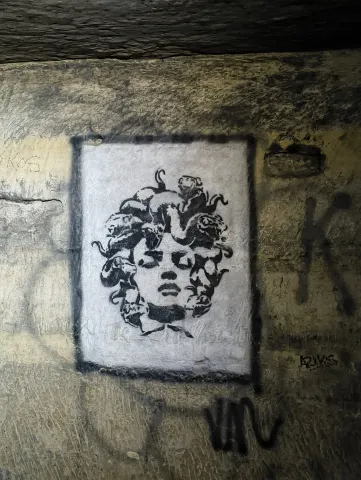 Tête de Méduse dessinée en noir et blanc dans un cadre peint sur la paroi
