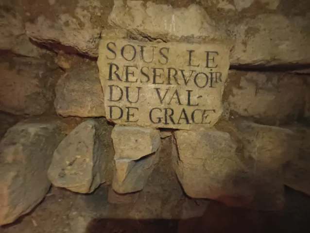 Plaque de pierre gravée « Sous le réservoir du Val-de-Grâce » posée dans un mur de blocs
