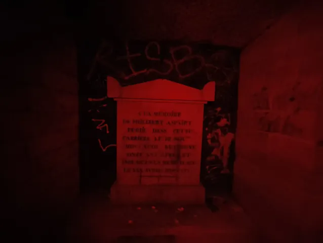 Stèle gravée d'une inscription commémorative, baignée d'une lumière rouge