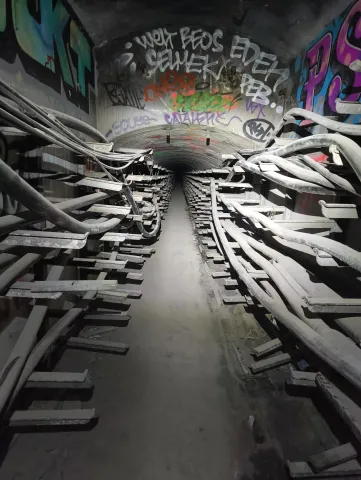 Tunnel bordé de consoles de câbles en enfilade, filant vers un point de fuite obscur
